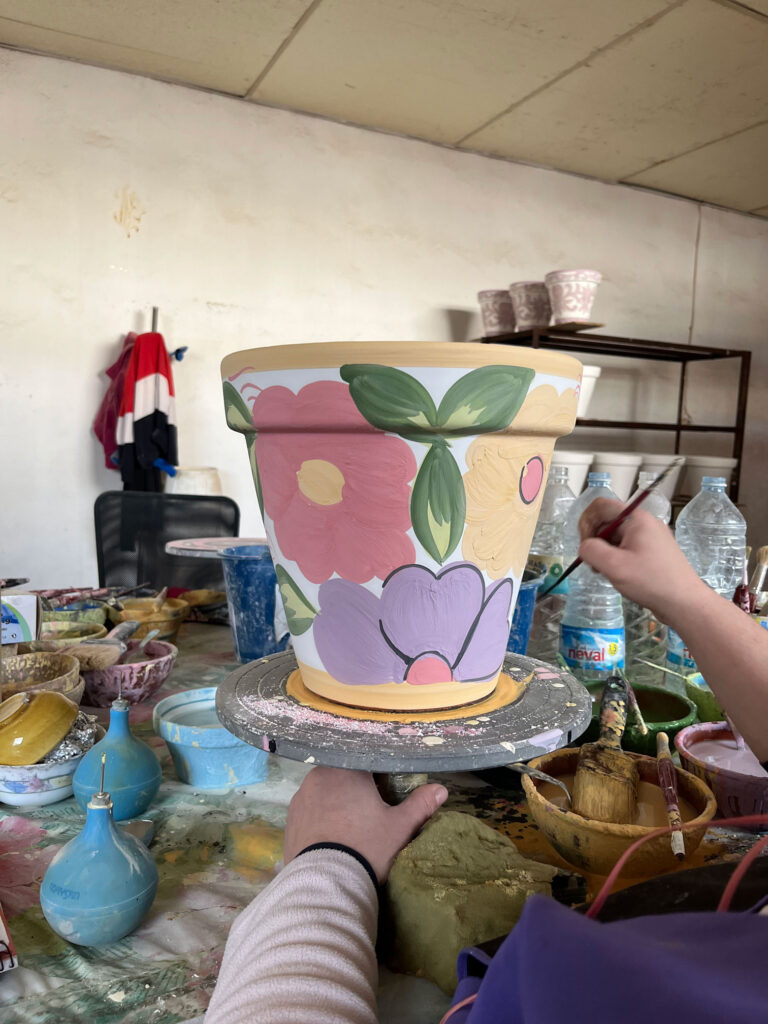 person hand decorating a flowerpot with a paintbrush